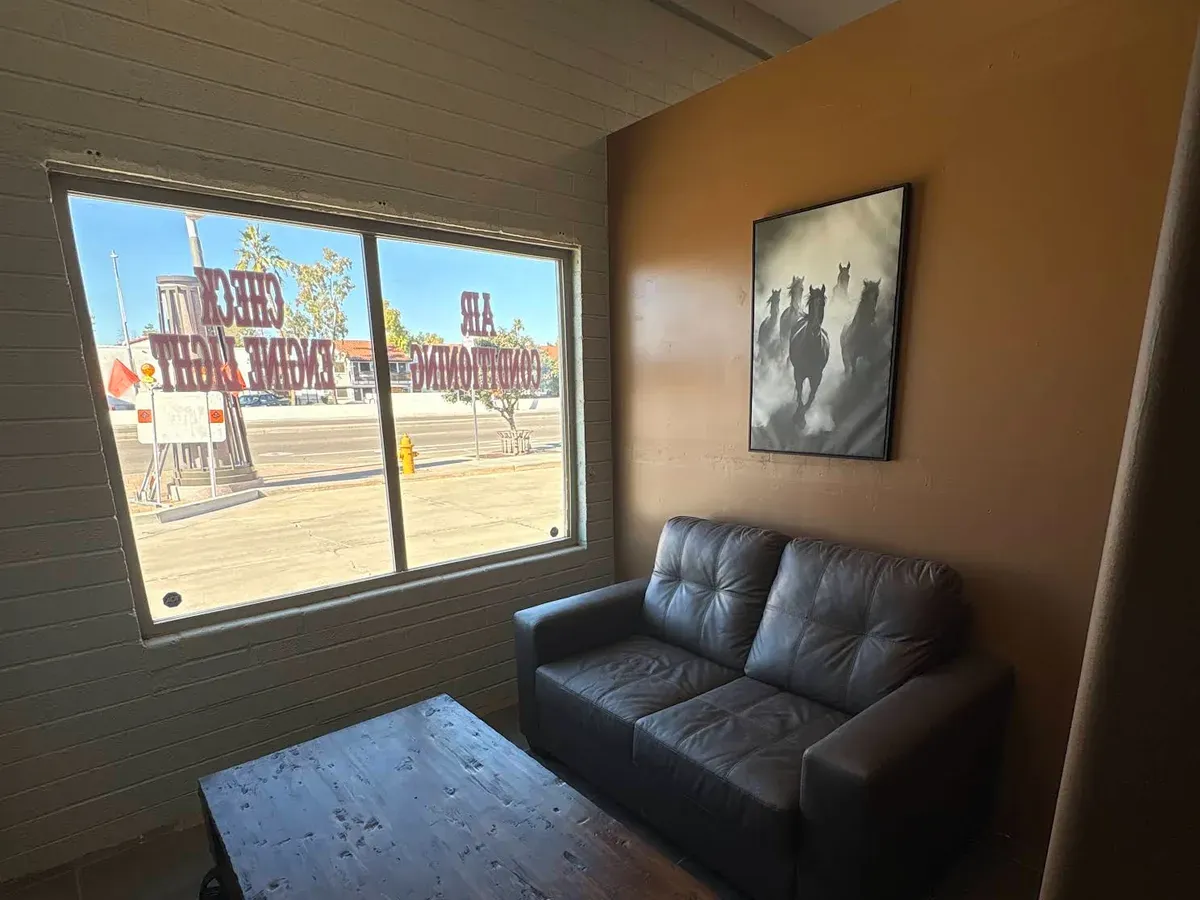 Lounge sofa and wood coffee table beside a window with A/C and check engine light lettering